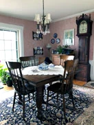 The dining room, with a chandelier over the table and a tall clock in the corner