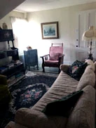 A sitting area with a sofa, a rocking chair and a patterned rug